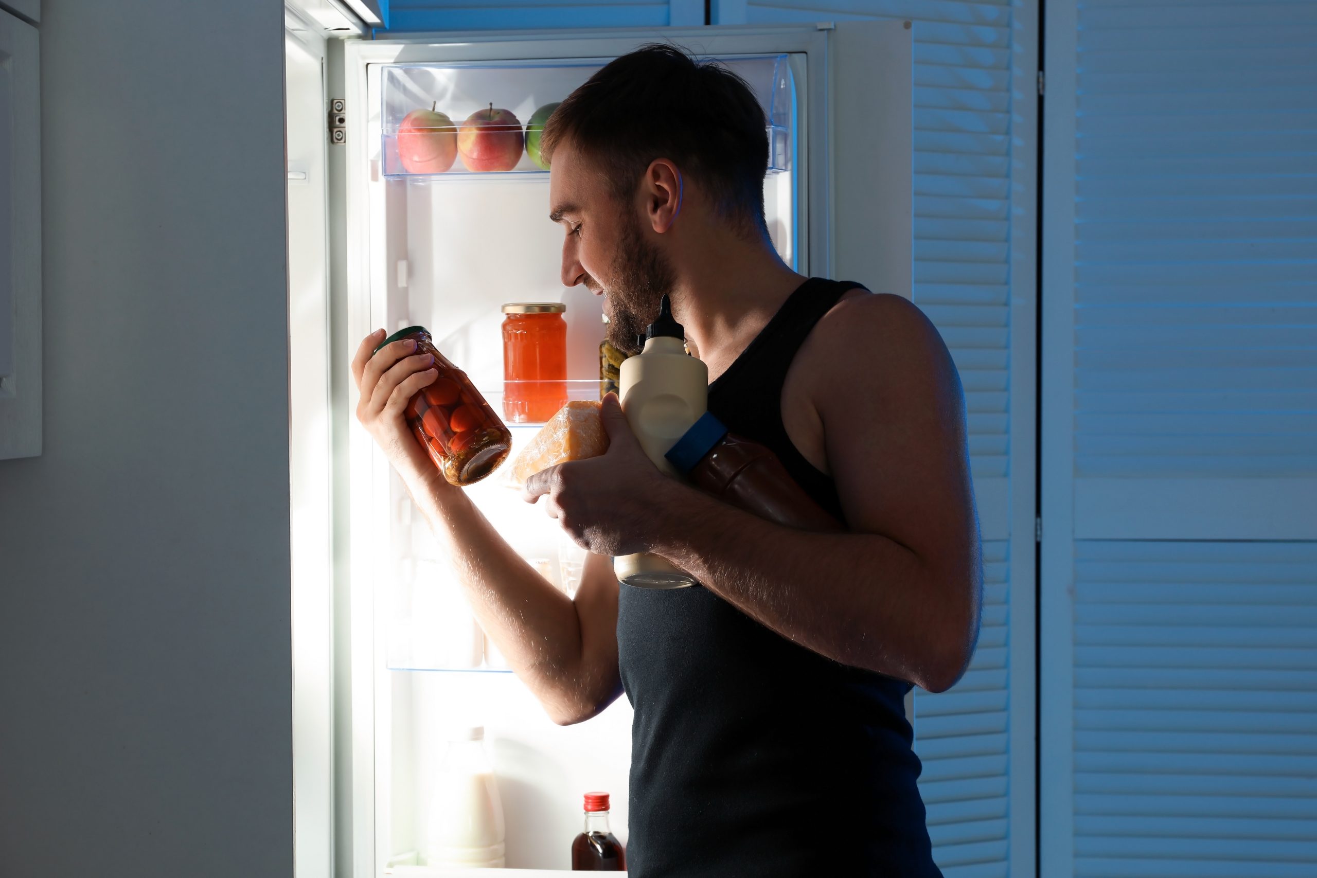 Man taking products out of refrigerator in kitchen at night