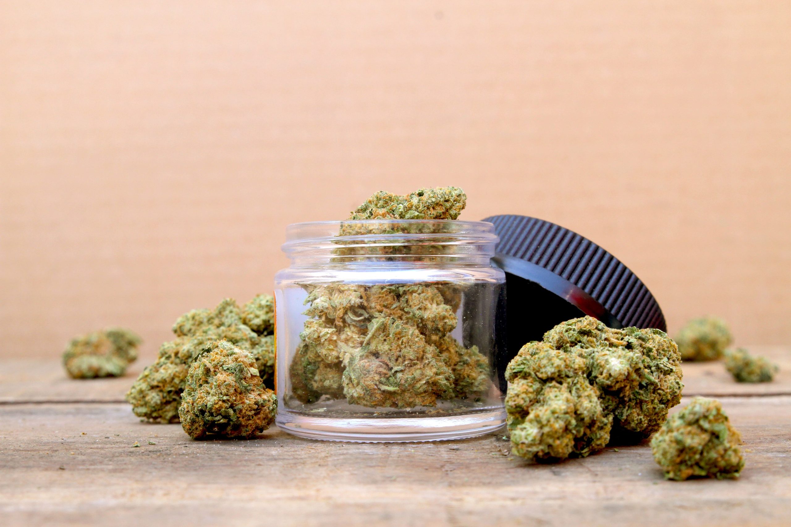 cannabis flower in a glass jar with black lid to the side